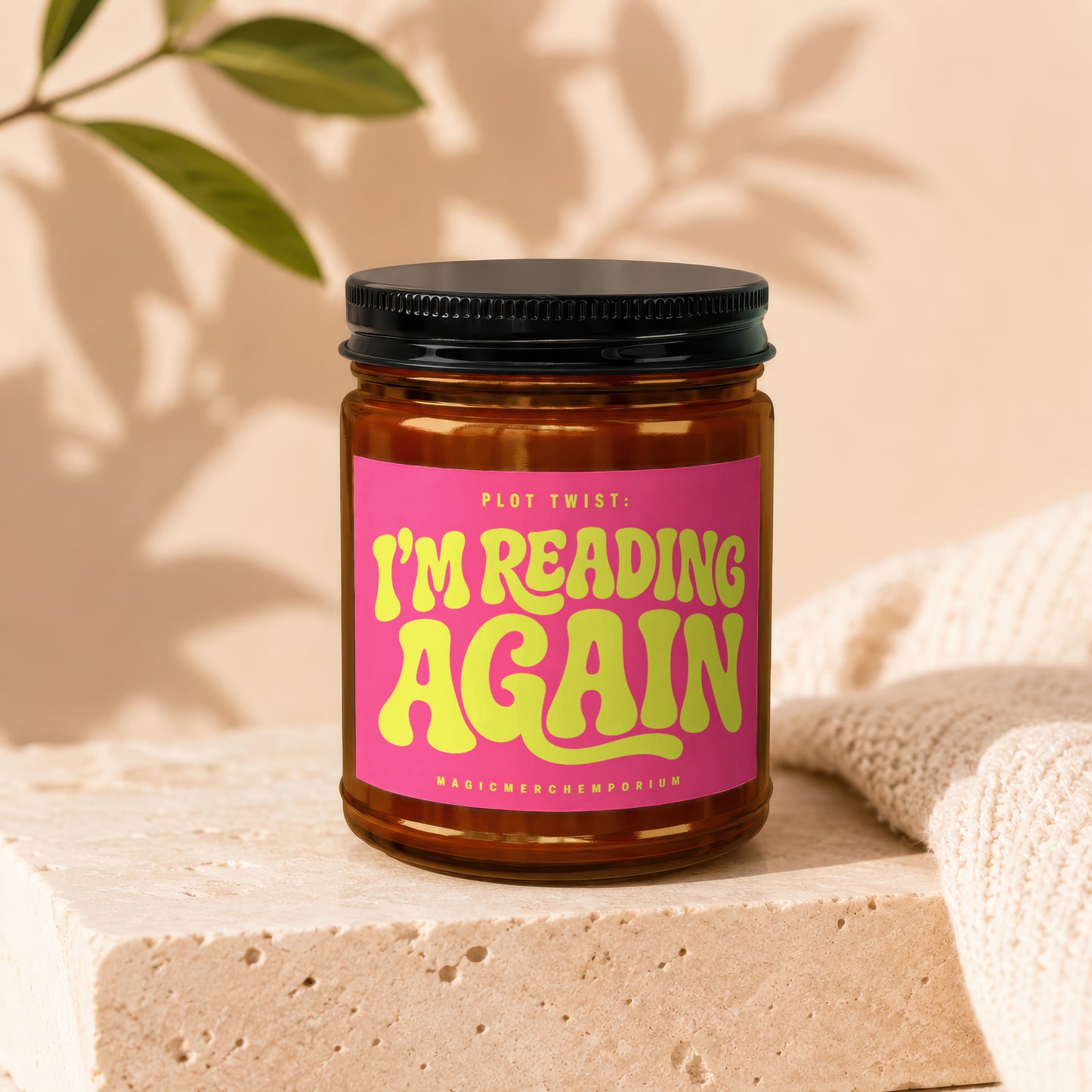Amber jar candle with pink label saying "PLOT TWIST: I'M READING AGAIN".
