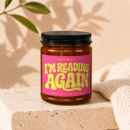 Amber jar candle with pink label saying "PLOT TWIST: I'M READING AGAIN".
