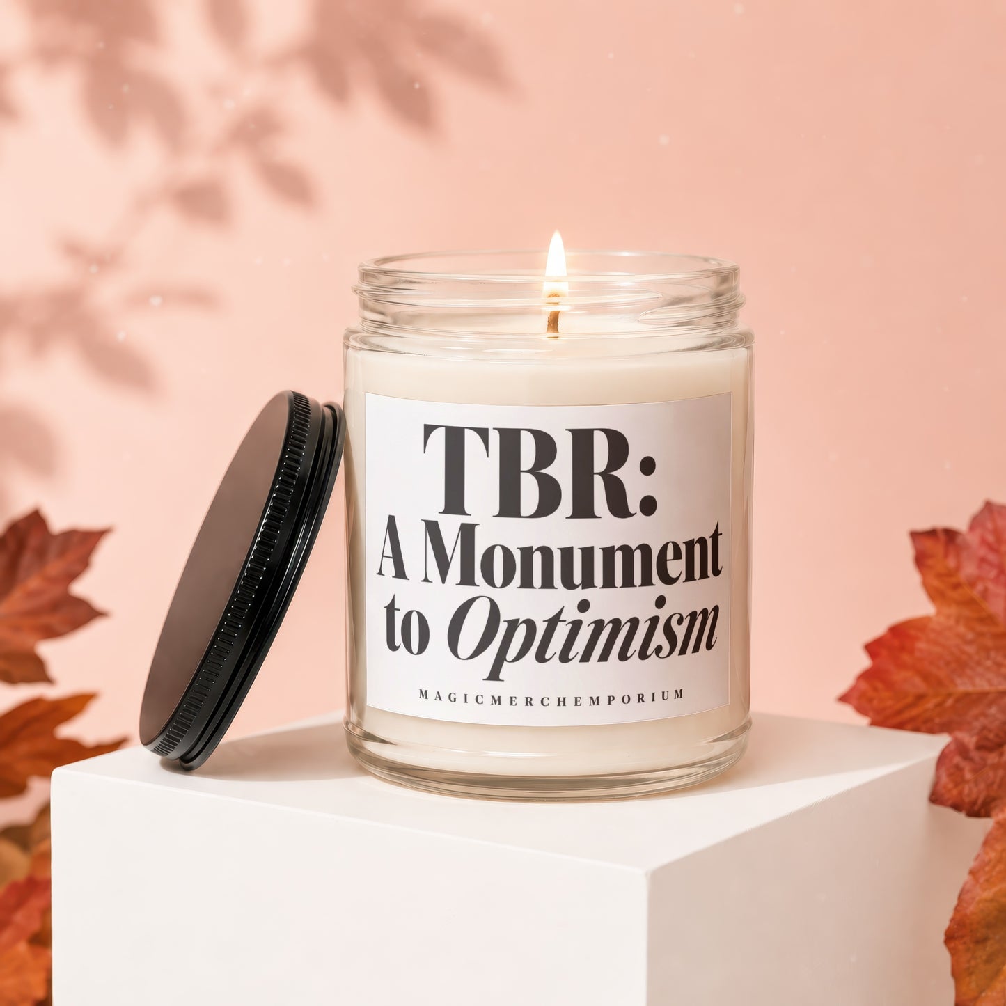 Candle with text "TBR: A Monument to Optimism" and "MAGICMERCHEMPORIUM" on label.