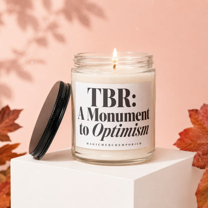 Candle with text "TBR: A Monument to Optimism" and "MAGICMERCHEMPORIUM" on label.