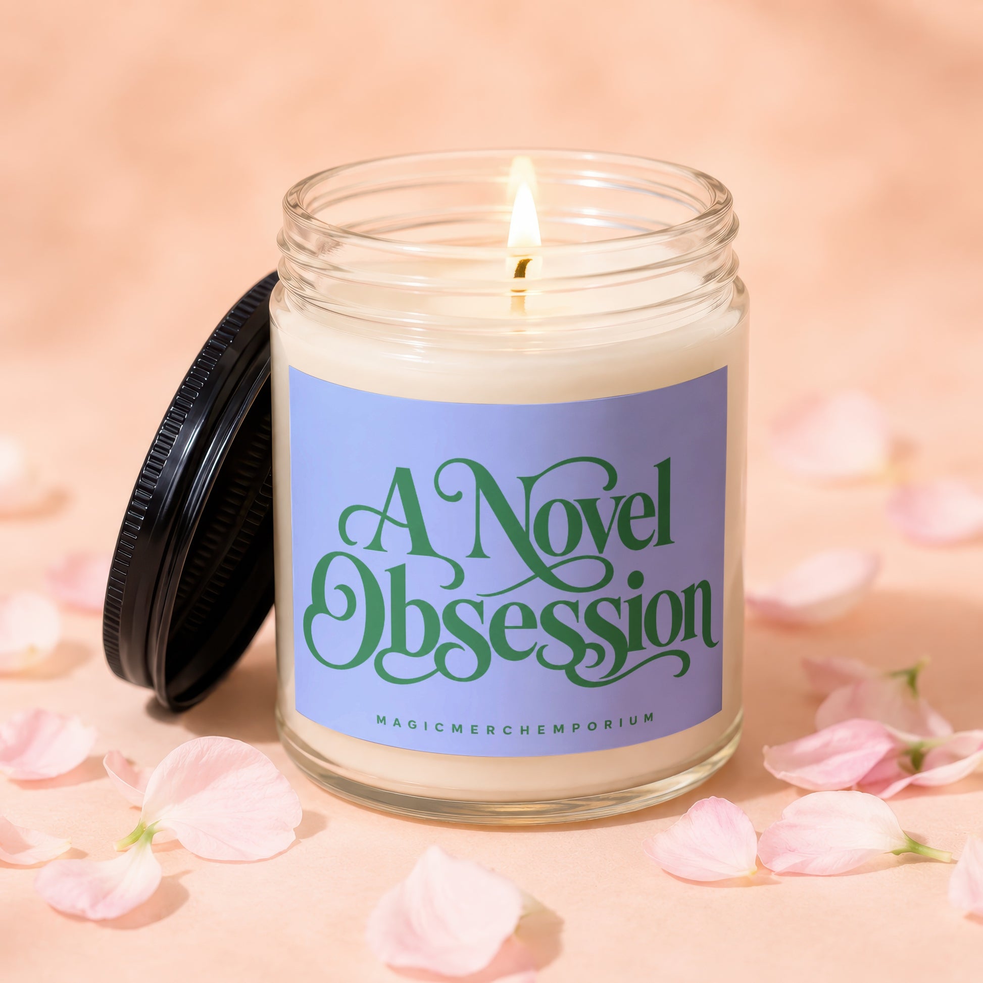Glass jar candle with lit wick and label text "A Novel Obsession MAGICMERCH"))EMPORIUM.