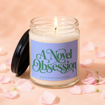 Glass jar candle with lit wick and label text "A Novel Obsession MAGICMERCH"))EMPORIUM.