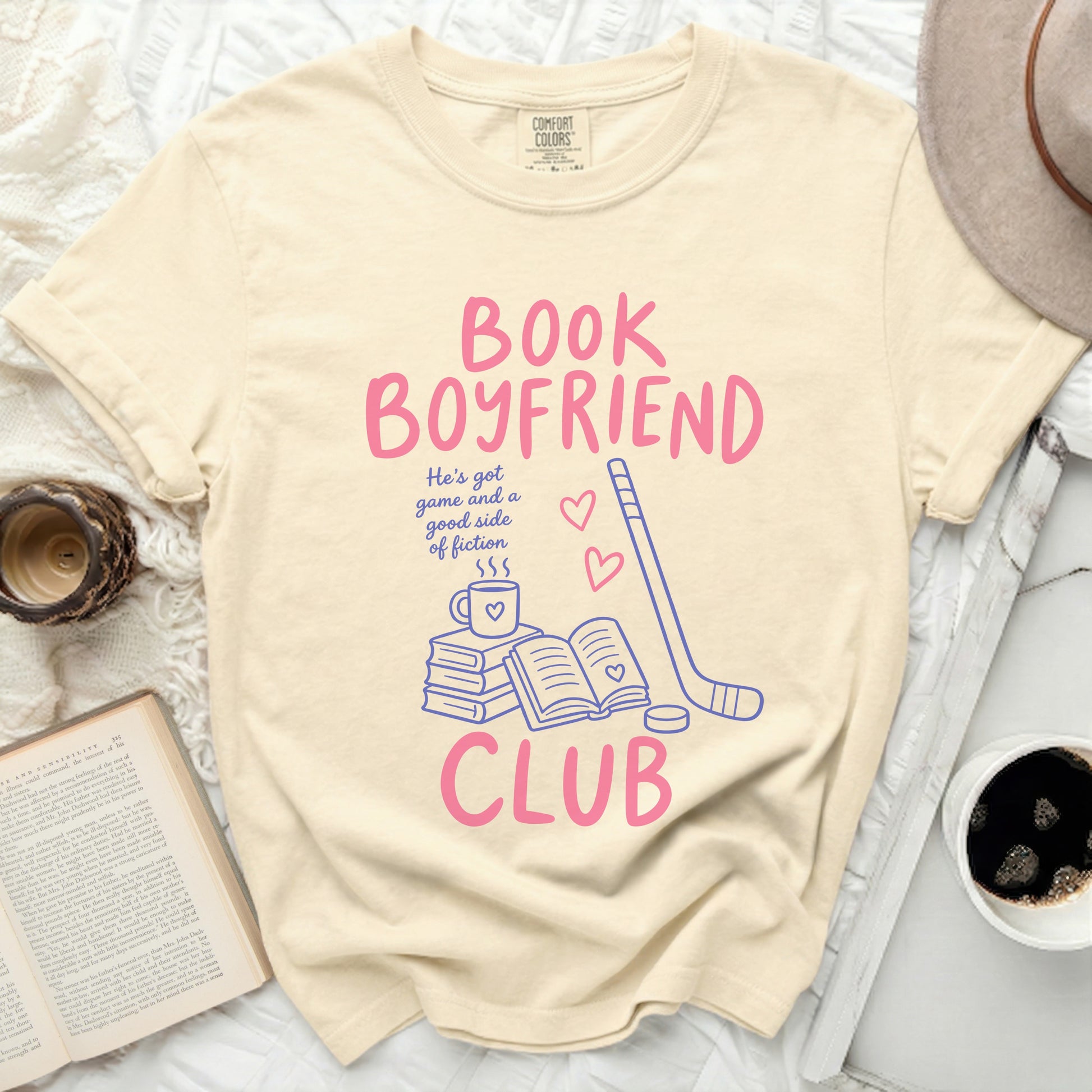 Cream t-shirt with "BOOK BOYFRIEND CLUB" text, book, and hockey stick graphics.