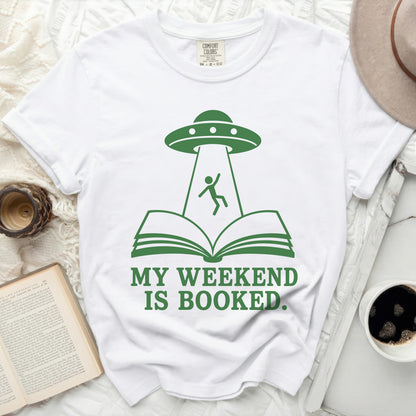 T-shirt with UFO beaming person from open book, text reads "MY WEEKEND IS BOOKED."