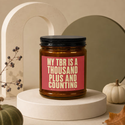 Amber candle with "MY TBR IS A THOUSAND PLUS AND COUNTING" text on pink label.