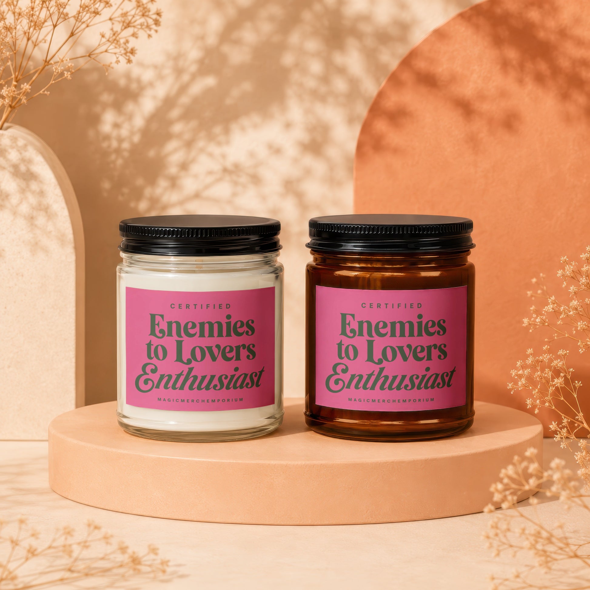Two candles featuring "Certified Enemies to Lovers Enthusiast" labels on pink backgrounds.