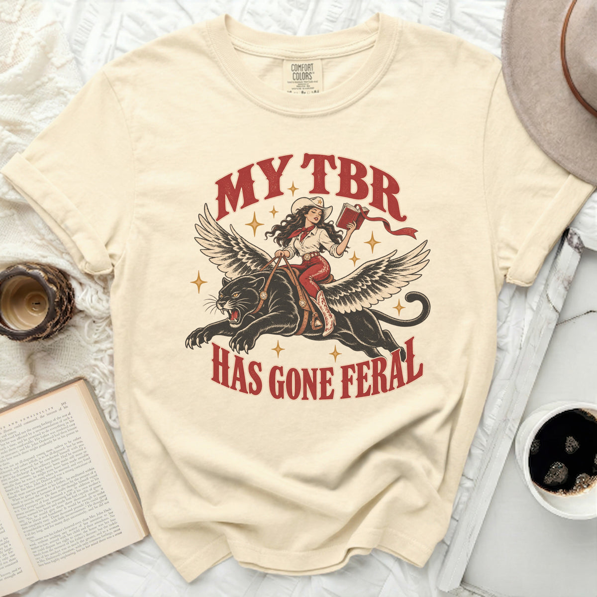 Cream t-shirt with "MY TBR HAS GONE FERAL" text and graphic.