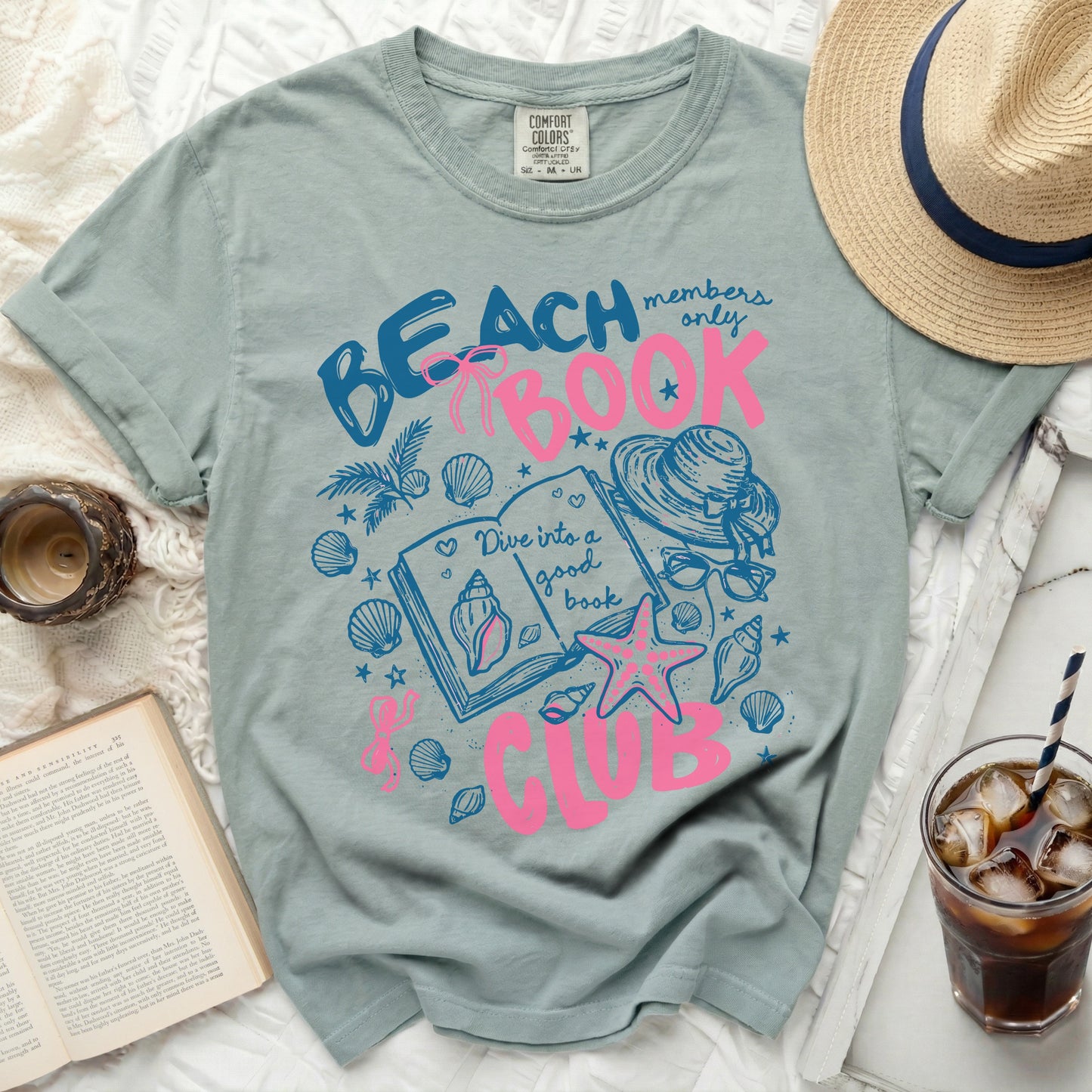 Blue t-shirt with pink graphic of a book, seashells, and "Beach Members Only Book Club" text.
