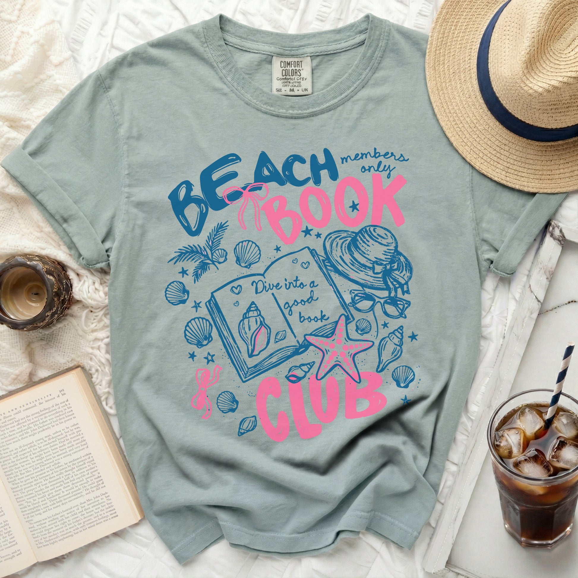 Blue t-shirt with pink graphic of a book, seashells, and "Beach Members Only Book Club" text.