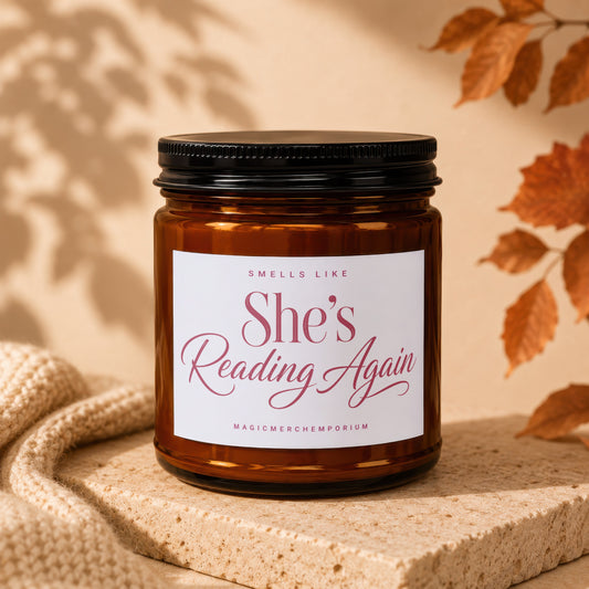 Amber glass candle with white label saying "She's Reading Again".