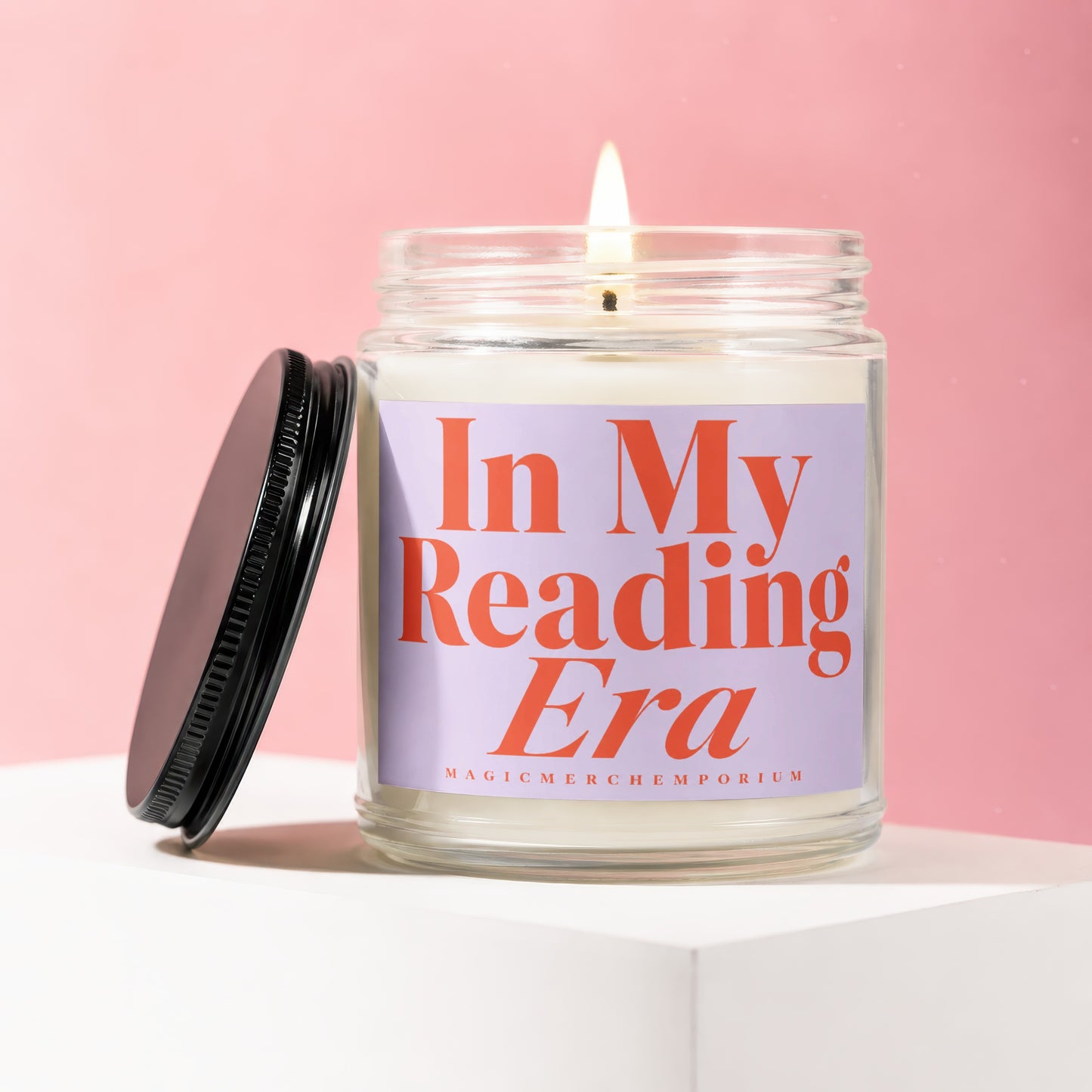 Candle labeled "In My Reading Era" with a lit wick on a pink background.
