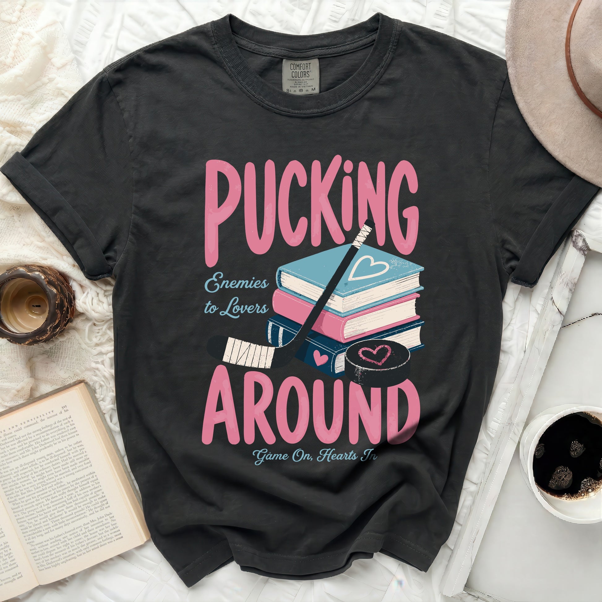 Black t-shirt with "Pucking Around" text, hockey stick, and books.