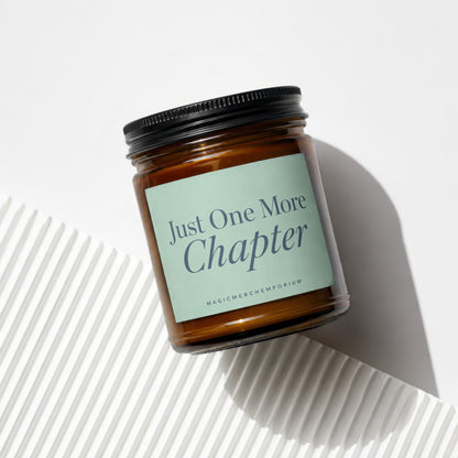 Amber glass candle with "Just One More Chapter" printed on label.