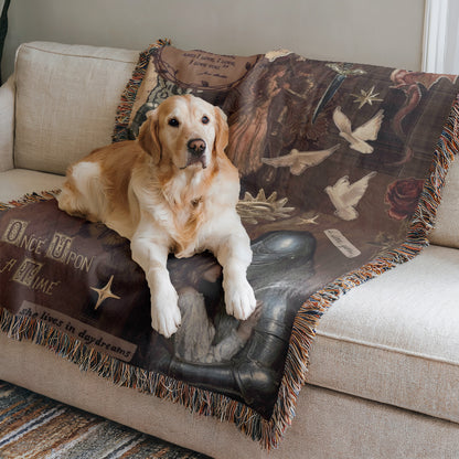 A golden retriever dog is lying on a couch, resting its head on a decorative blanket with a book-themed design.