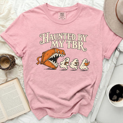 Pink t-shirt with "Haunted By My TBR" text and book monster chasing ghosts.