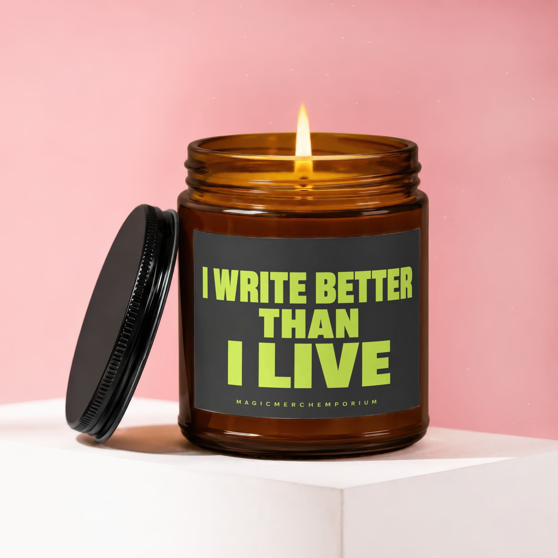 Amber glass candle with lit flame and text "I write better than I live".
