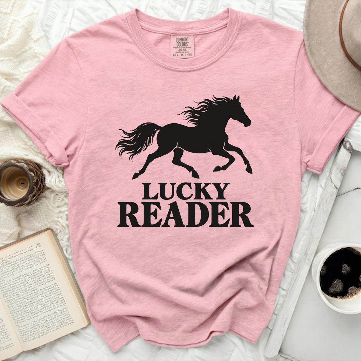 Pink t-shirt with black silhouette of a running horse and text "LUCKY READER".