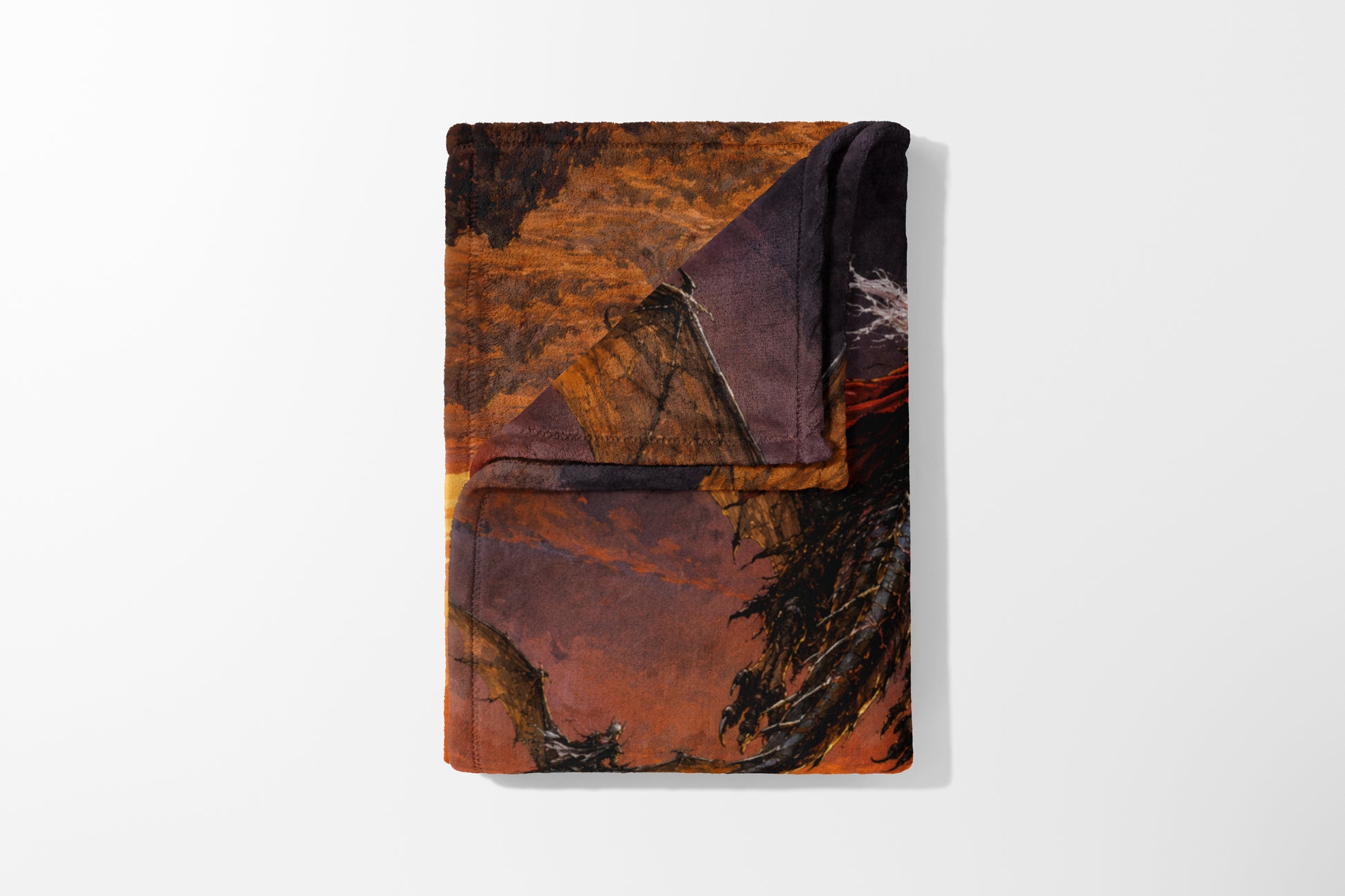 Folded blanket featuring a dragon in a dramatic, fiery landscape scene.
