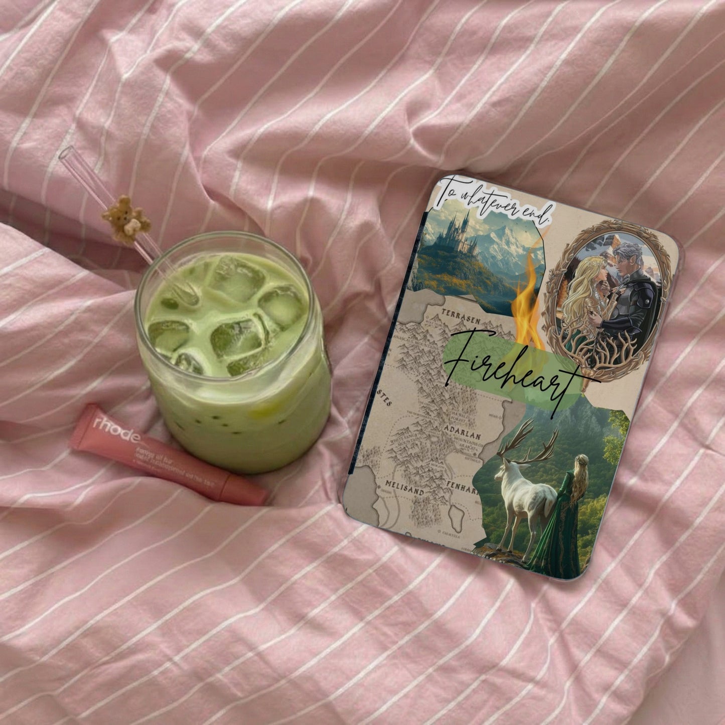 Notebook with fantasy art, map, and "Fireheart" title, next to matcha drink and lip balm.