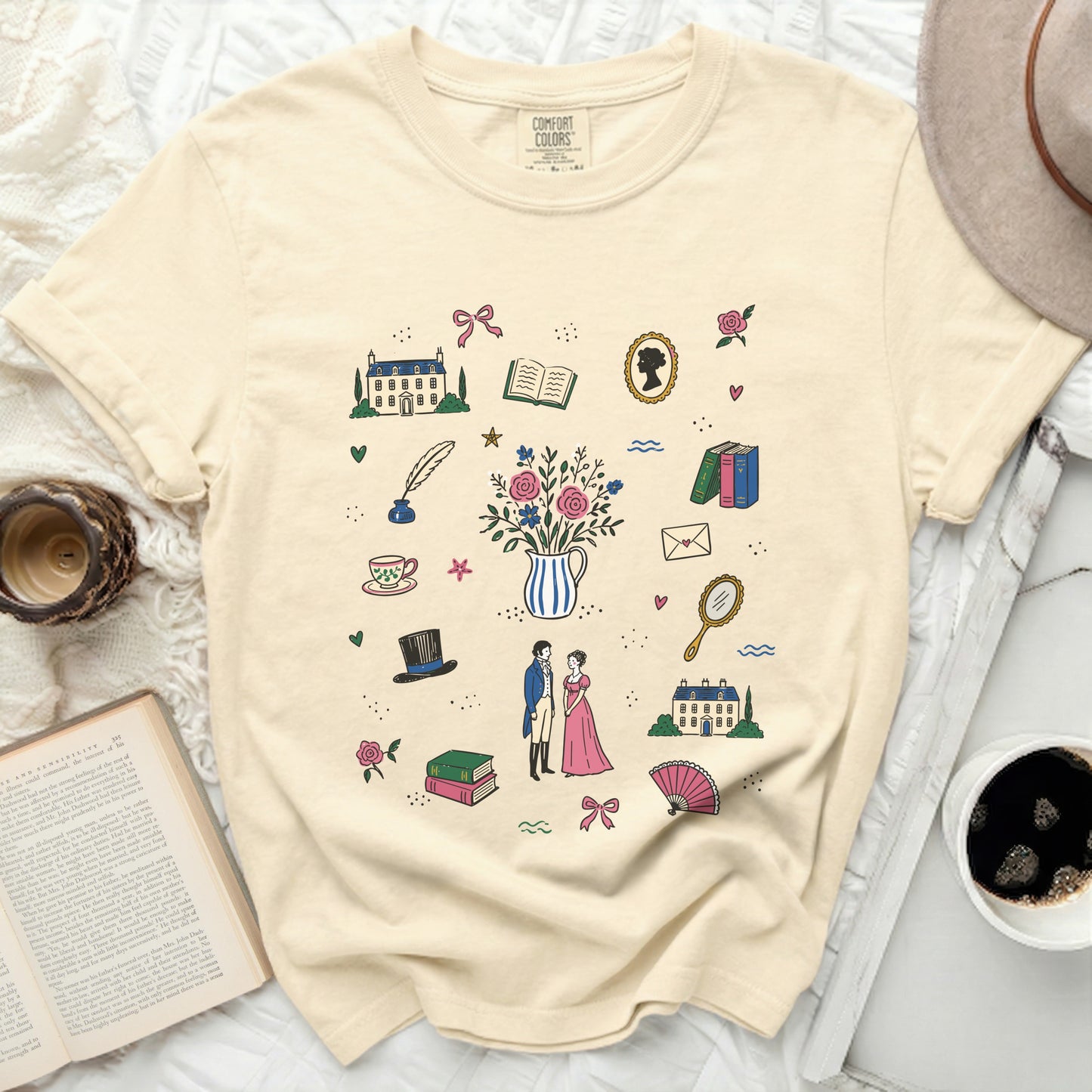 Cream t-shirt with a print of vintage illustrations including houses, books, and people.