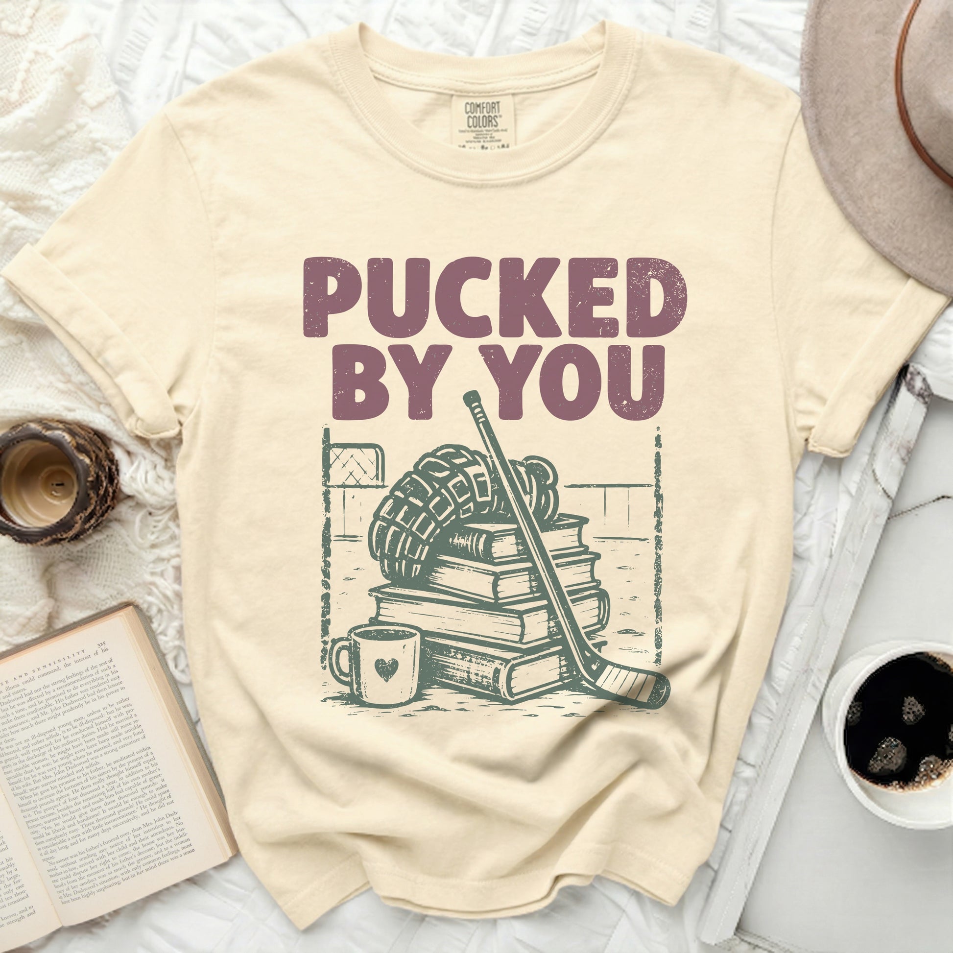 Cream t-shirt with "Pucked By You" text and hockey gear illustration.