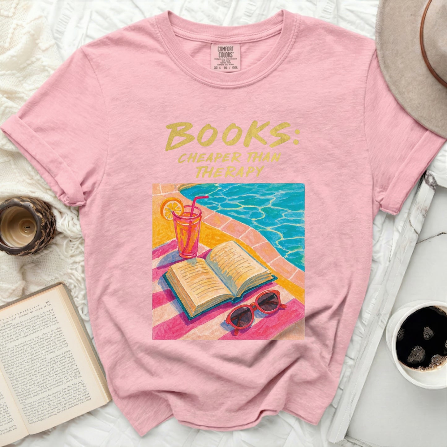 Pink t-shirt with "BOOKS: CHEAPER THAN THERAPY" text and pool scene graphic.