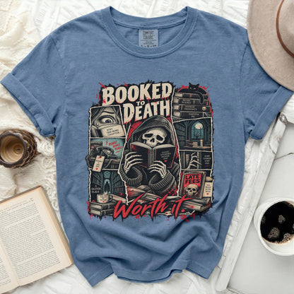 Shirt graphic with grim reaper reading, books, and text "Booked to Death" and "Worth it."