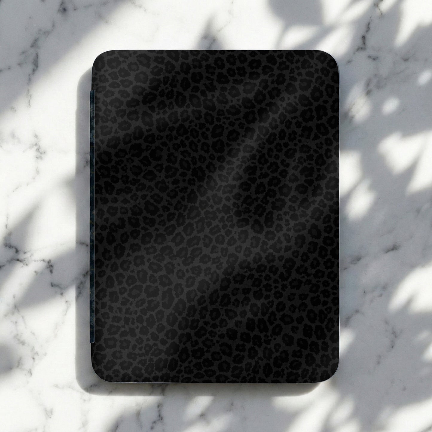 Dark gray black leopard print electronic device cover on marble surface.