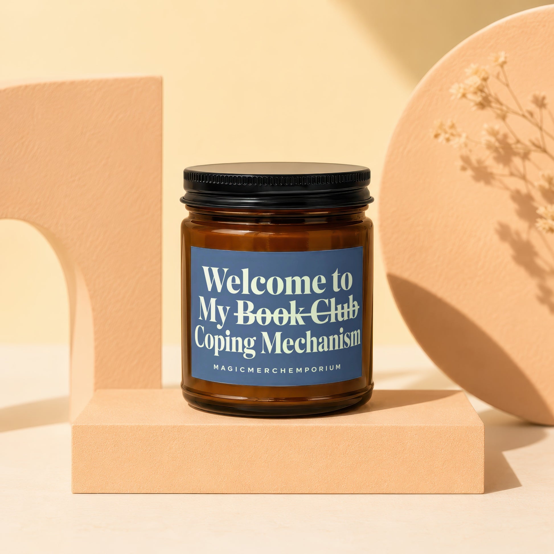 Amber jar candle with blue label reading "Welcome to My Book Club Coping Mechanism".