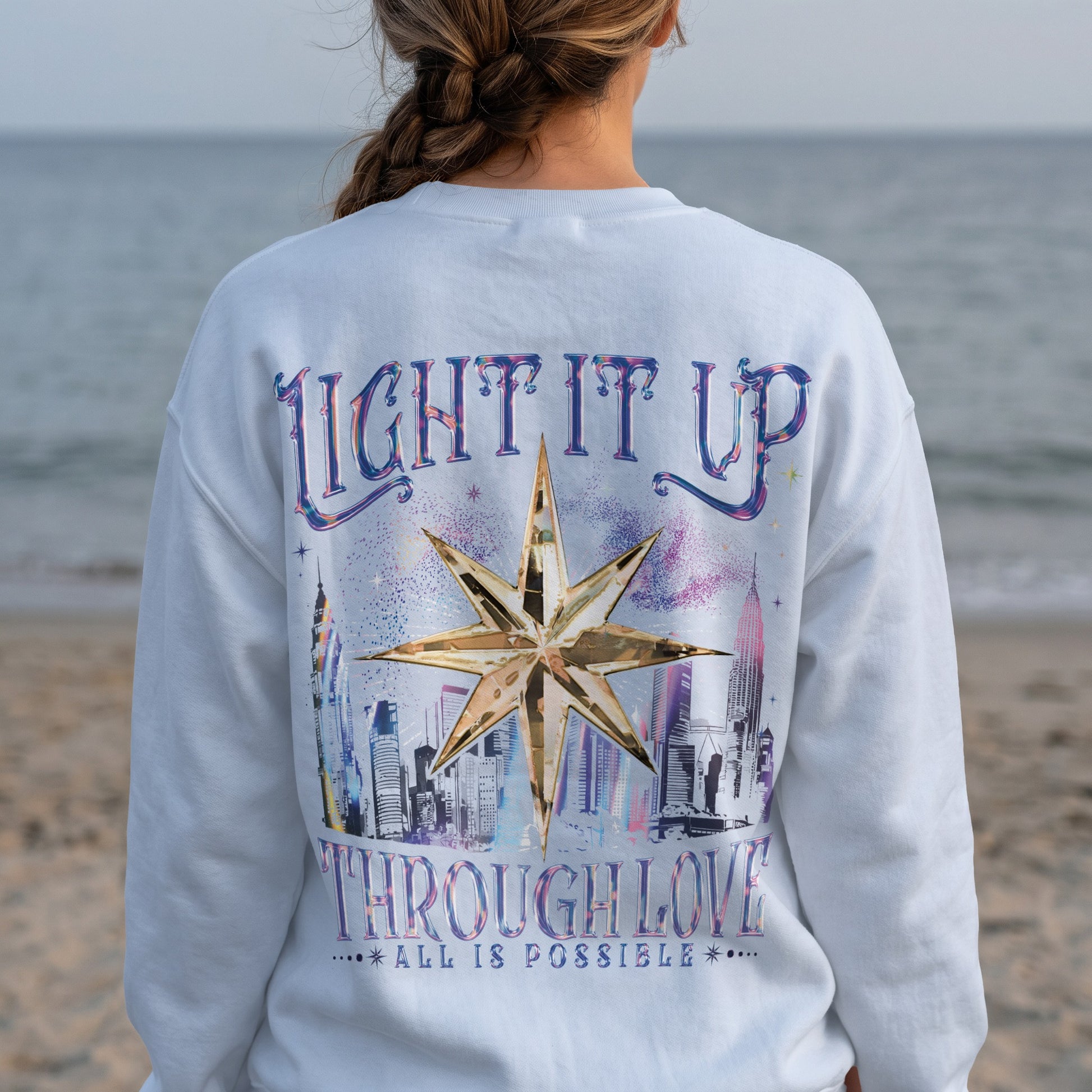 Crewneck sweatshirt with "Light It Up Through Love" and a gold star over a city skyline.
