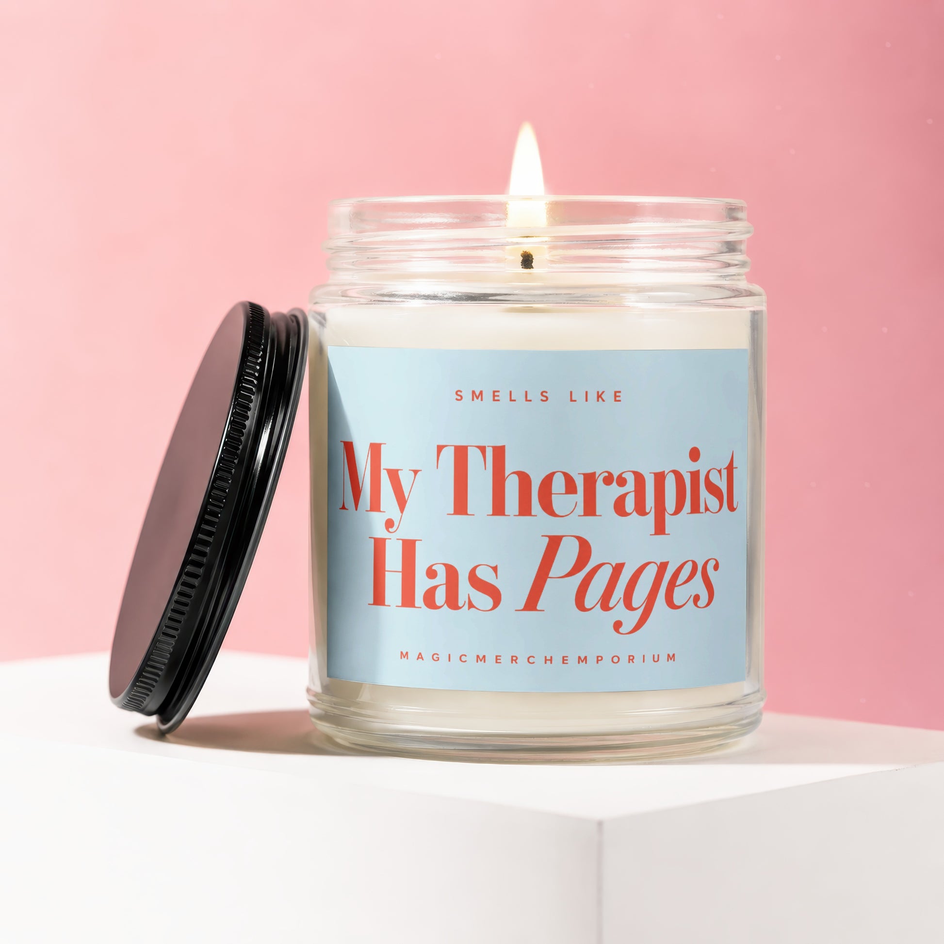 Scented candle with lit wick and lid off, featuring "My Therapist Has Pages" text.