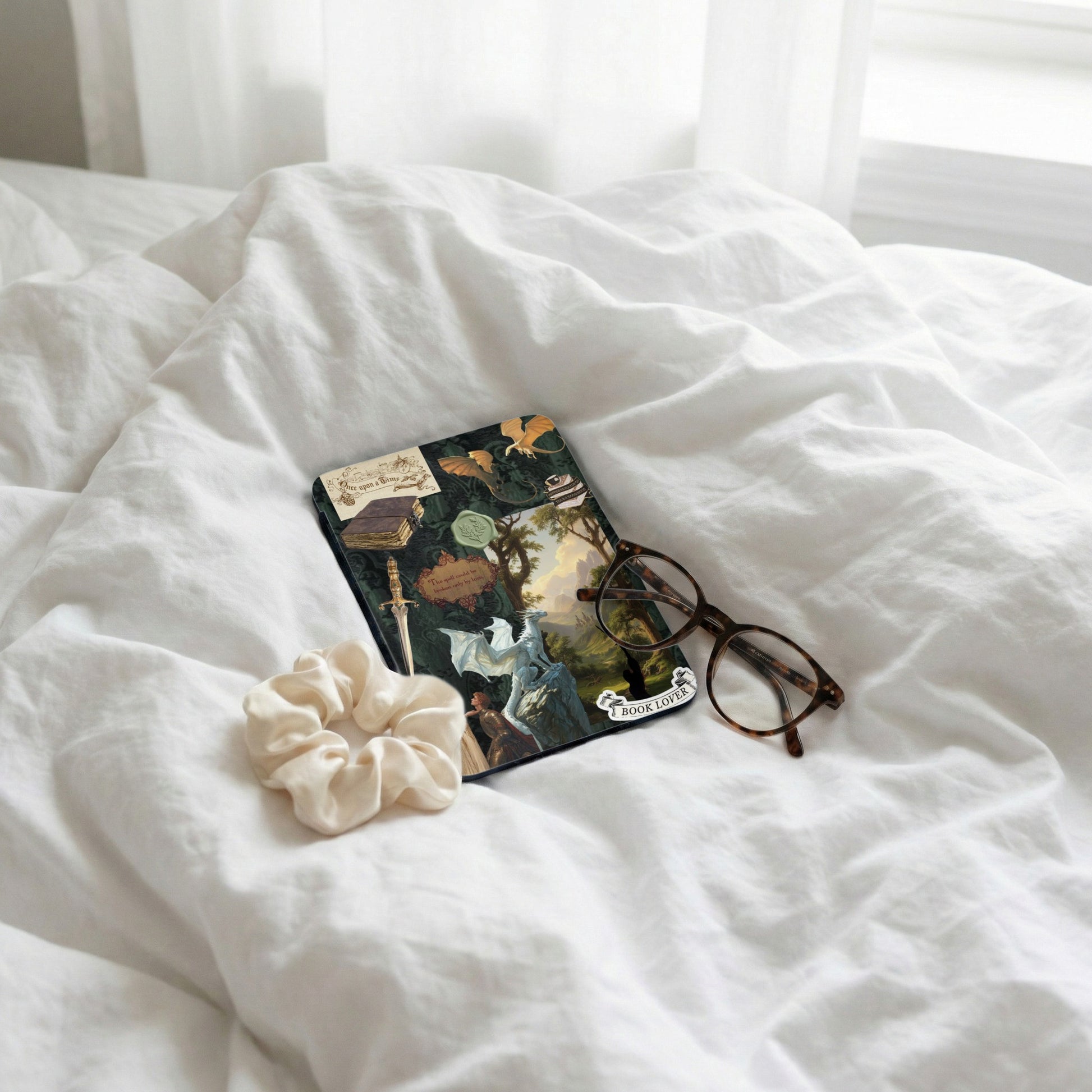 Journal decorated with dragons, a sword, and vintage book illustrations, with glasses and scrunchie.