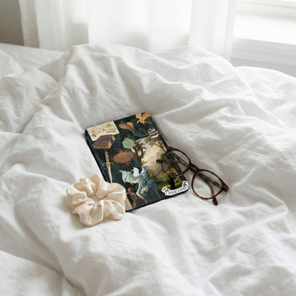 Journal decorated with dragons, a sword, and vintage book illustrations, with glasses and scrunchie.