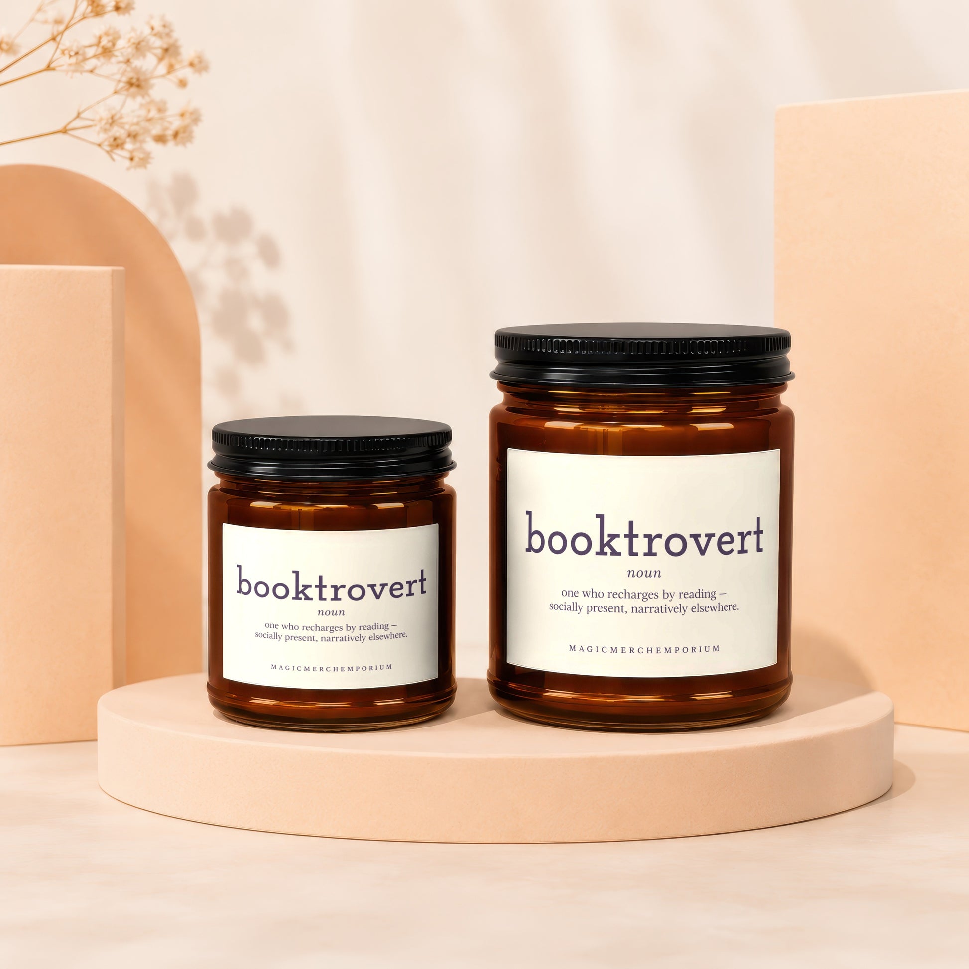 Two amber glass candles with black lids, labeled "booktrovert."