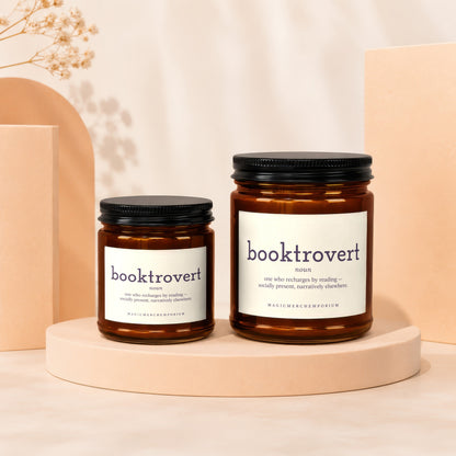 Two amber glass candles with black lids, labeled "booktrovert."
