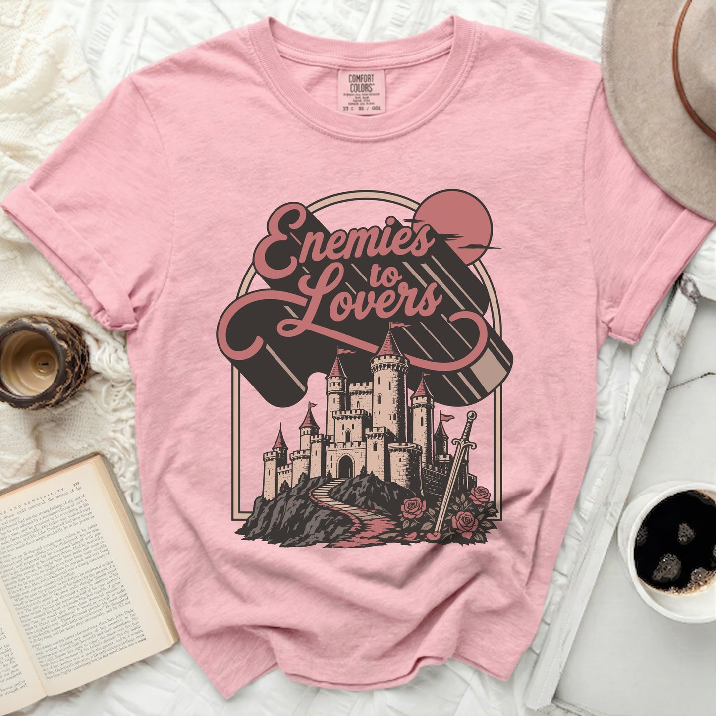 Pink Comfort Colors t-shirt with "Enemies to Lovers" castle graphic.
