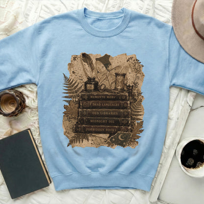 Light blue sweatshirt with Memento Mori stack of books, moth, and hourglass print.