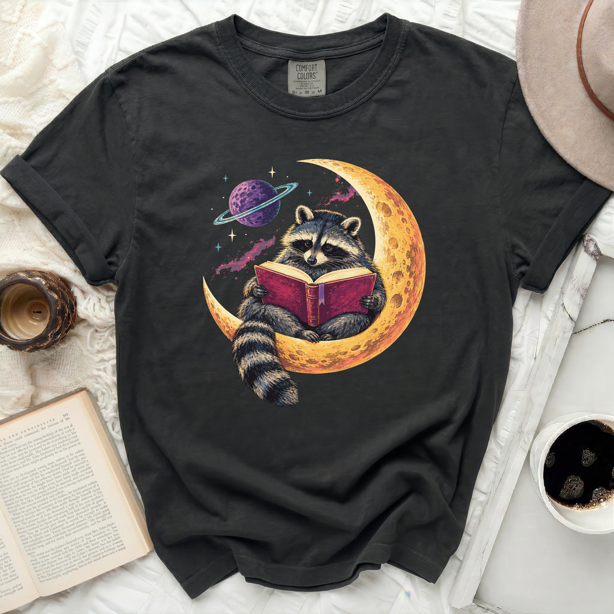 Raccoon reading a book on the moon with a planet in the background.