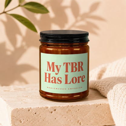 Candle with "My TBR Has Lore" text and "MAGICMERCH EMPORIUM" on light green label.