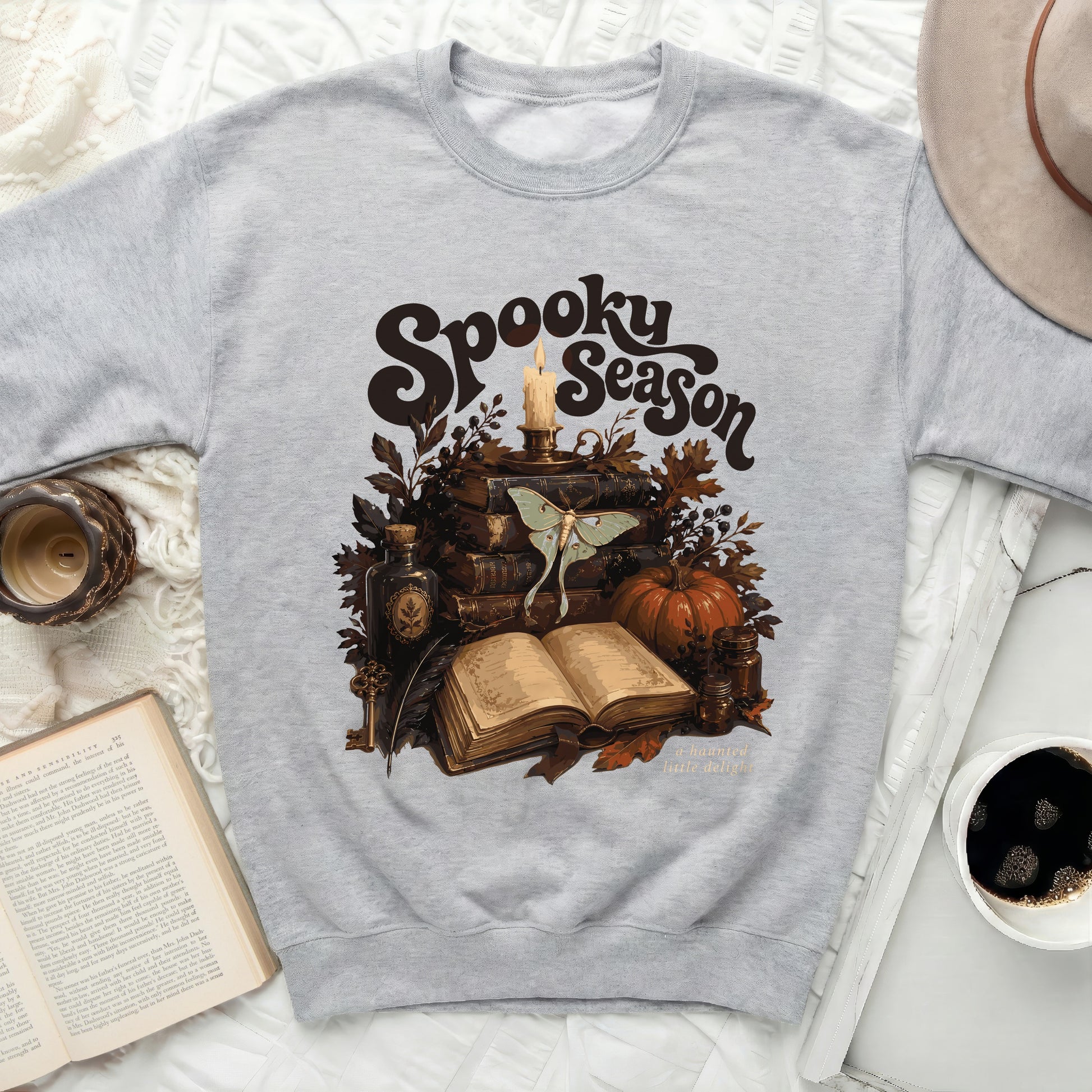 Grey sweatshirt with "Spooky Season" art featuring books, moth, candle, and pumpkin.