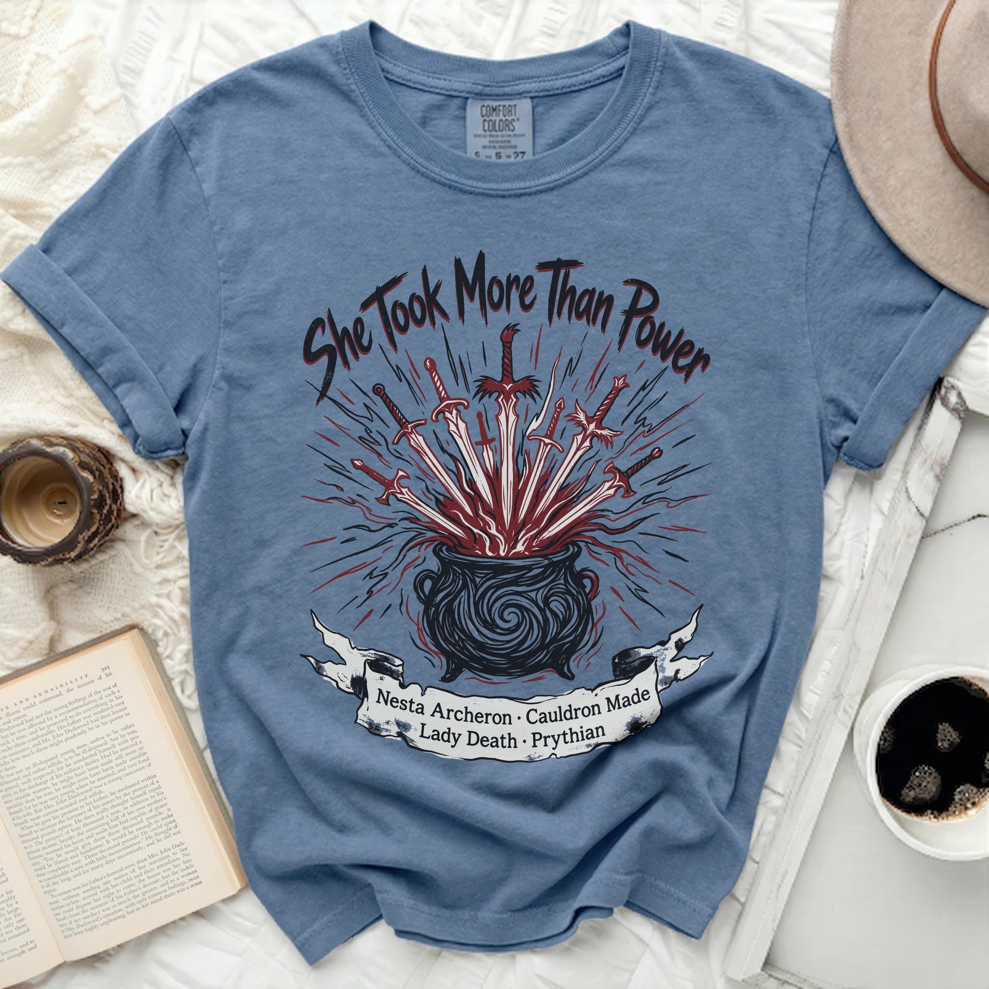 Blue t-shirt with "She Took More Than Power" and cauldron graphic.