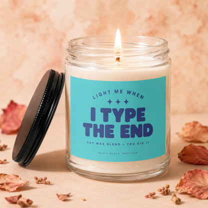 Jar candle with "I TYPE THE END" text, lit wick, and black lid.