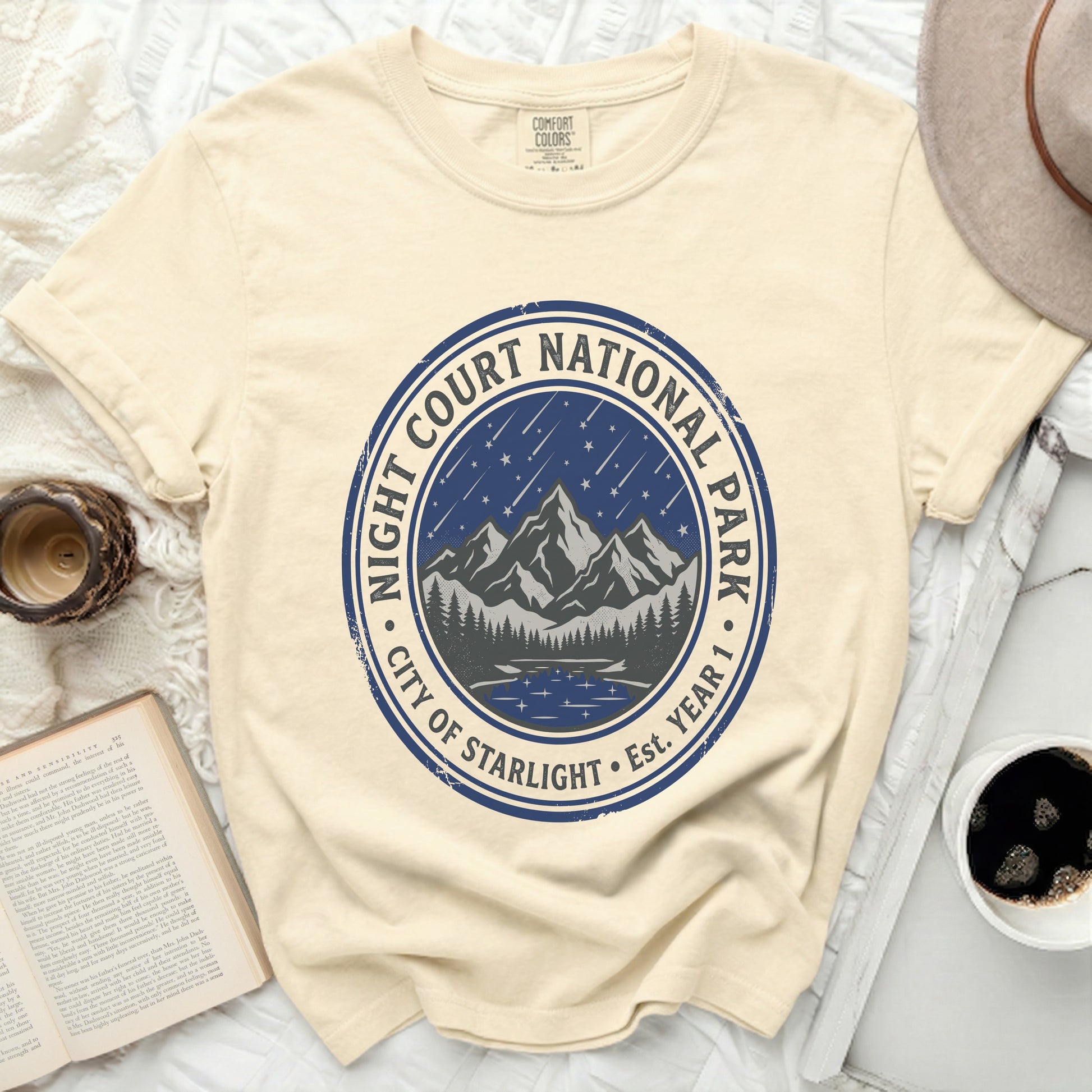 Cream t-shirt with blue circular logo for Night Court National Park, City of Starlight.