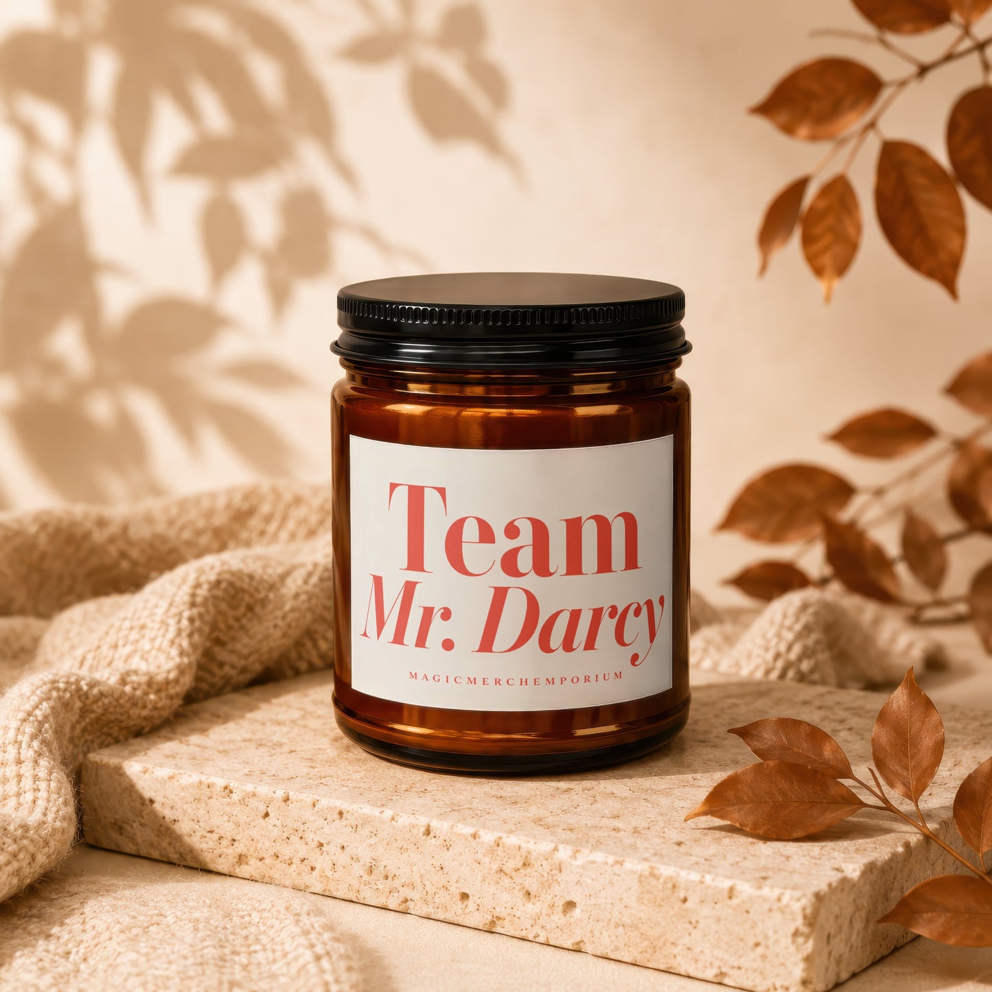 Amber candle with black lid labeled "Team Mr. Darcy" on stone pedestal.