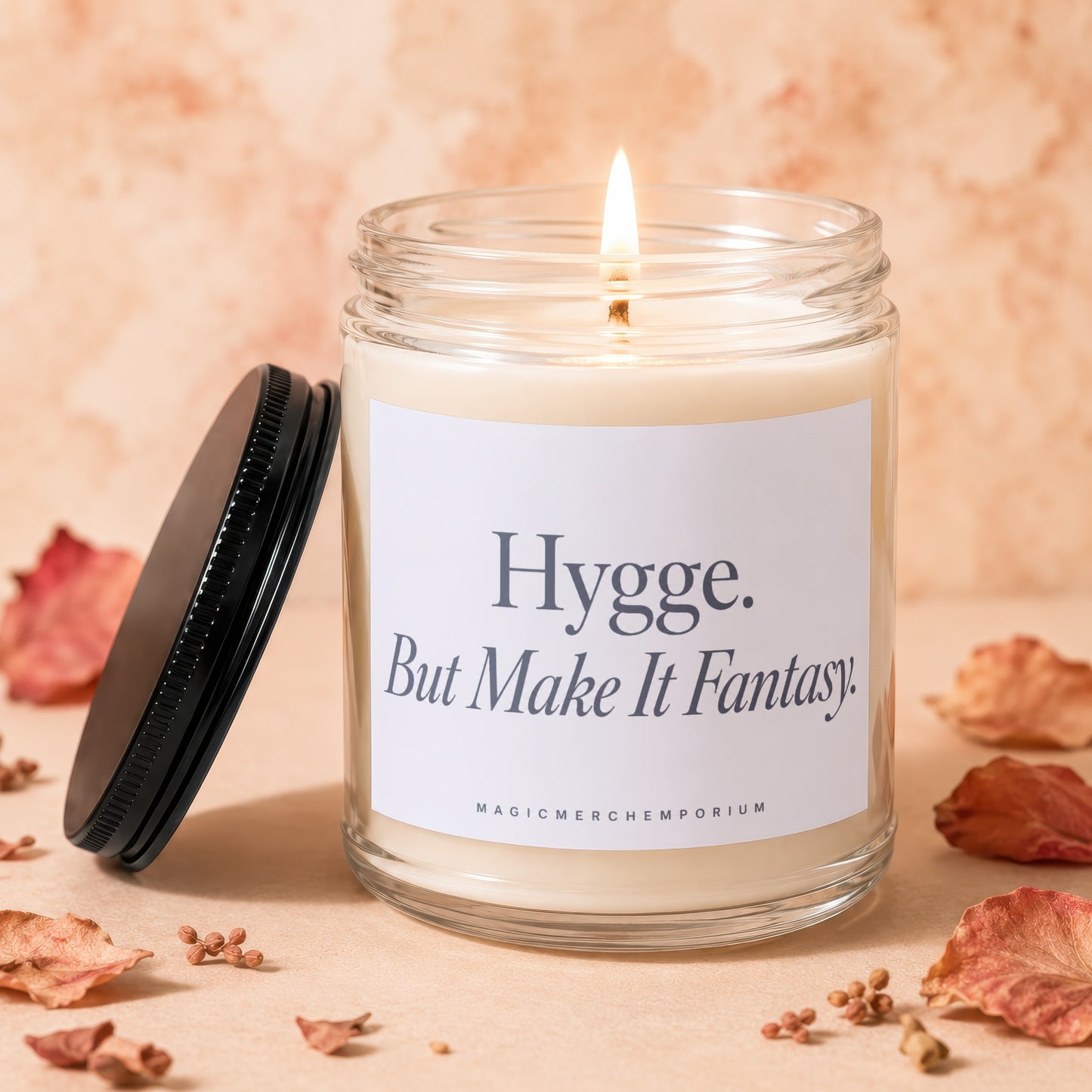 Glass jar candle with lit wick, labeled "Hygge. But Make It Fantasy."