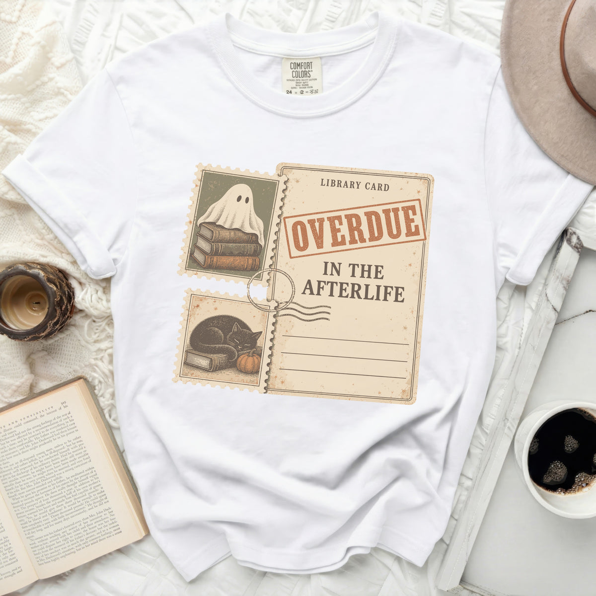 White t-shirt with "Overdue In The Afterlife" library card graphic featuring ghost and black cat.