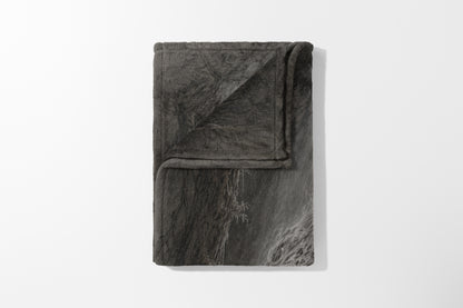 Folded grey blanket with a cracked stone pattern and a fuzzy texture.