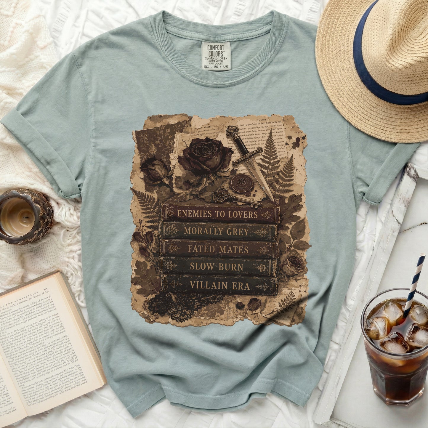 T-shirt with a collage design of roses, dagger, keys, and book titles like "Enemies to Lovers."