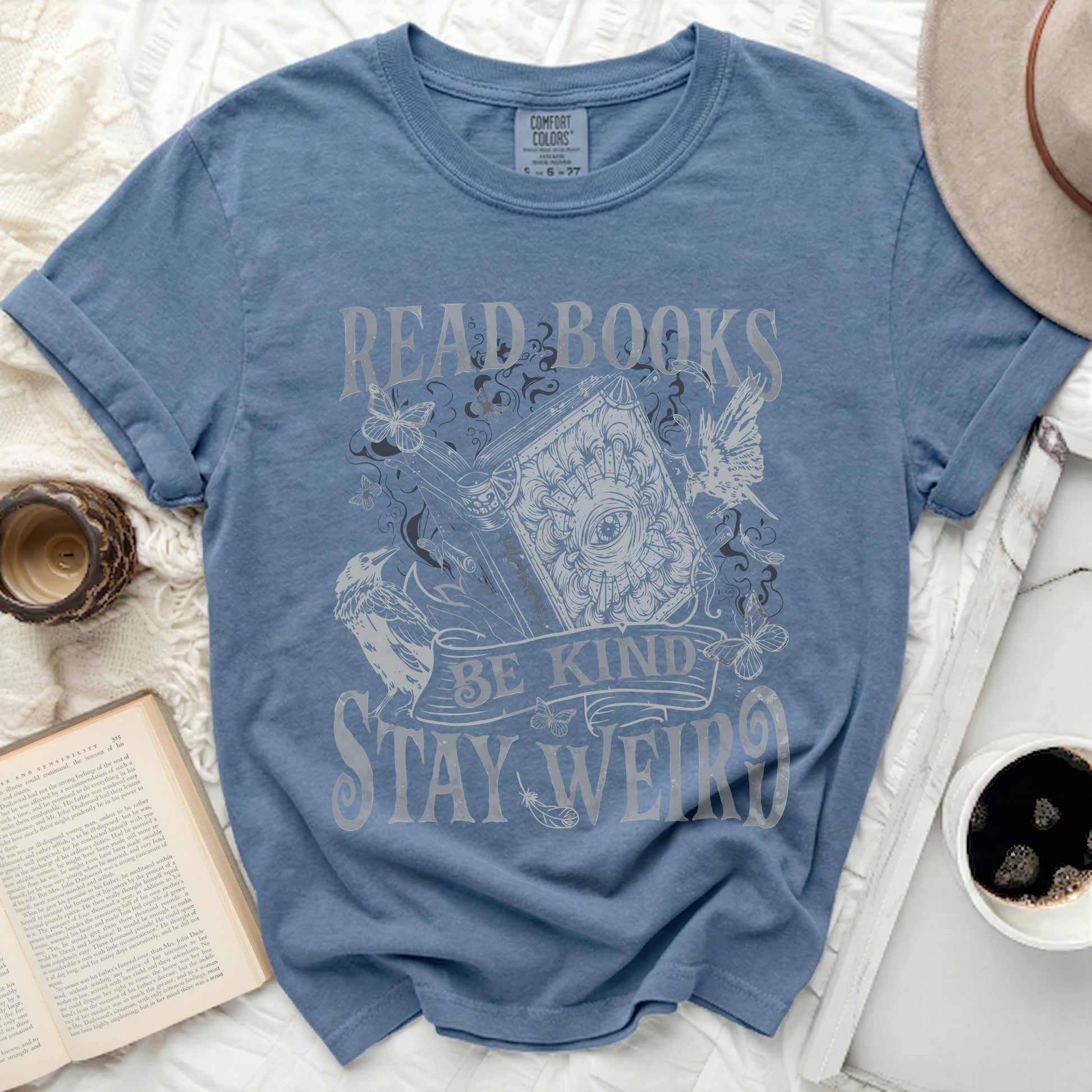 Blue t-shirt with "Read Books, Be Kind, Stay Weird" text and illustrations.