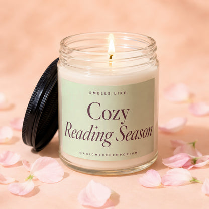 Glass candle with lit wick and lid off, labeled "Cozy Reading Season".